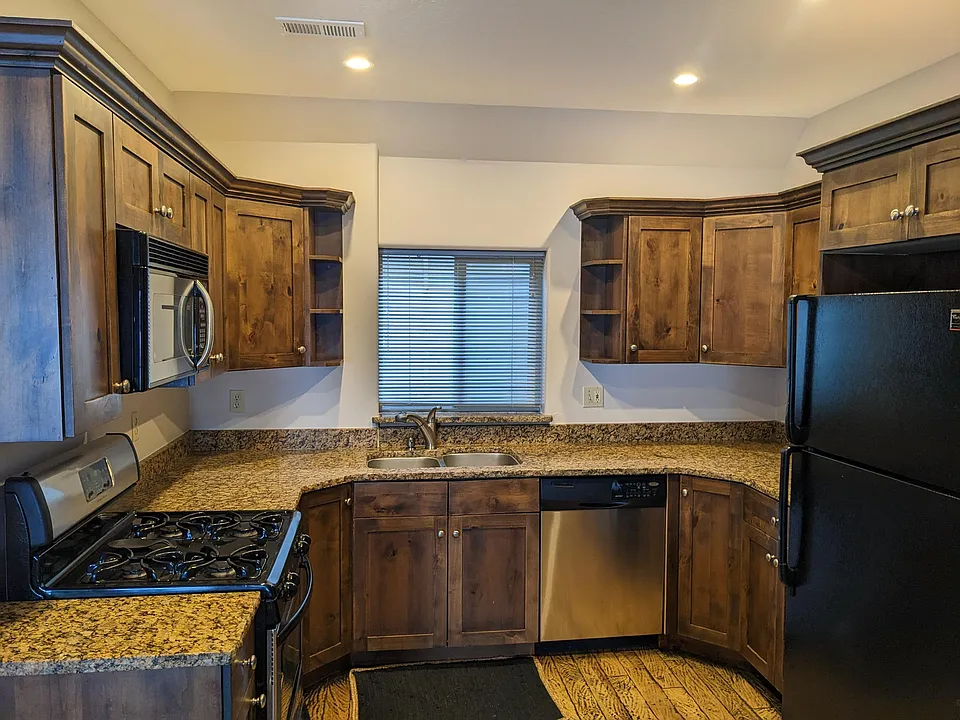 Kitchen with stove, microwave, dishwasher, and refridgerator/freezer. Window leads to back yard