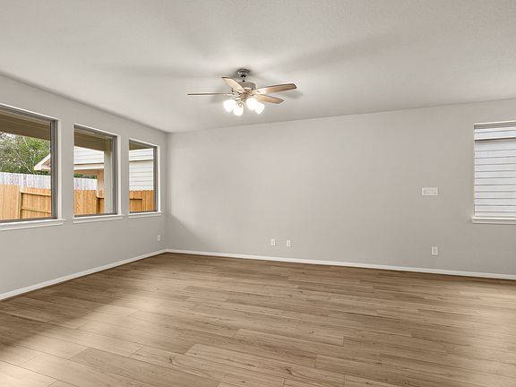 An additional view of your family room featuring a ceiling fan, gorgeous flooring and large windows.