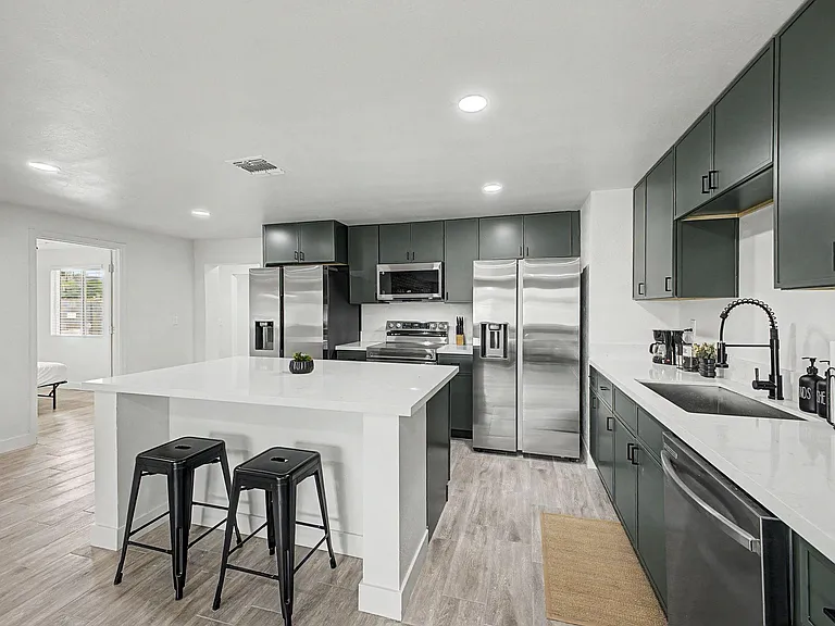 Spacious kitchen with large island seating, quartz-style counters, dark cabinetry, and stainless steel appliances.