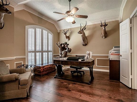 The formal dining room with engineered wood floors, ceiling fan, plantation shutters, chair rail, and picture frame molding.  The door on the right opens to the breakfast area and the kitchen.
