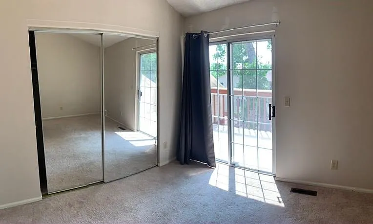 Bedroom 1 with balcony, vaulted ceiling, and connected bathroom.