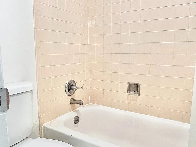 Bright and clean bathroom with modern fixtures, featuring a pristine shower-tub combo and elegant tile work.