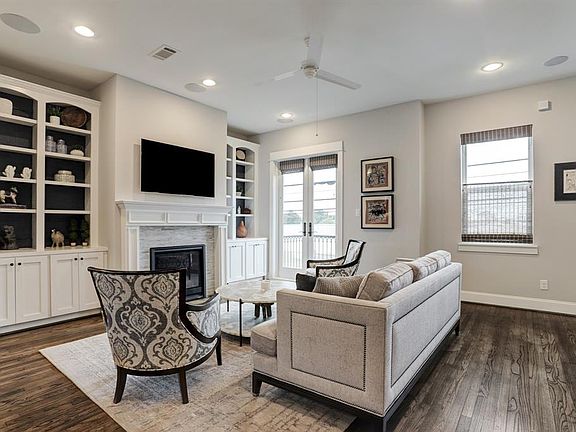 Beautiful second floor living area is warm and inviting with reclaimed hardwood floor, soaring ceiling, custom built-in bookcases, and a gas-log fireplace with decorative glass tile surround.