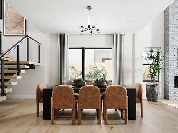 A modern and minimalist dining room with a wooden table and chairs, a large window overlooking a nat