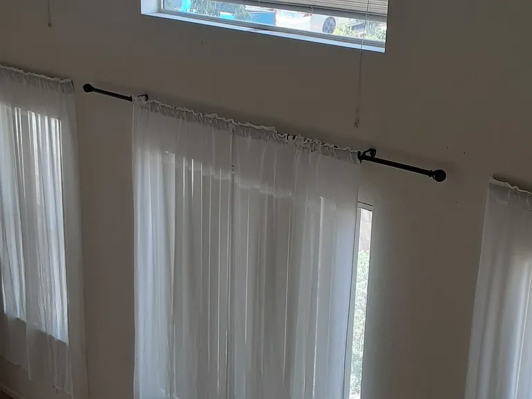 The Living room windows covered with blinds and fashionable curtains