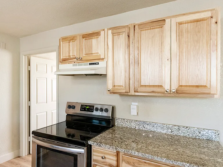 ELECTRIC RANGE WITH SELF CLEANING OVEN, HICKORY CABINETS & GRANITE COUNTERTOPS.