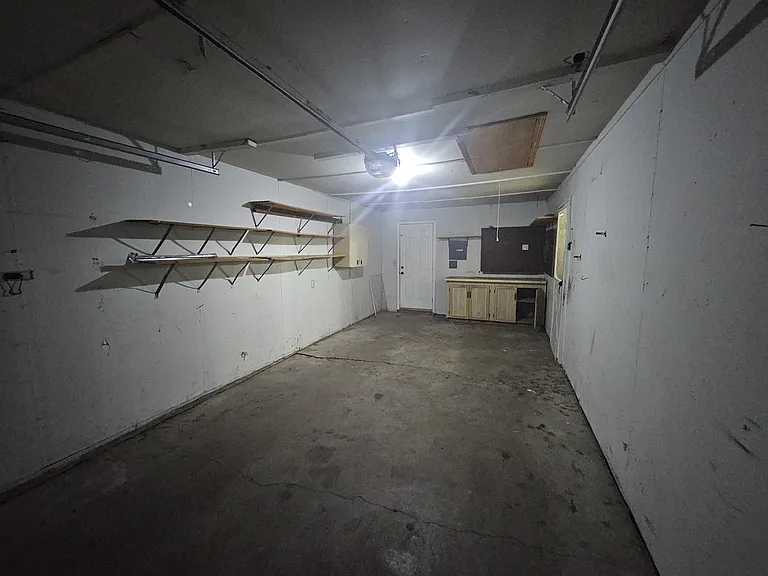 Garage - view from front showing workbench, additional cabinets, and shelving.