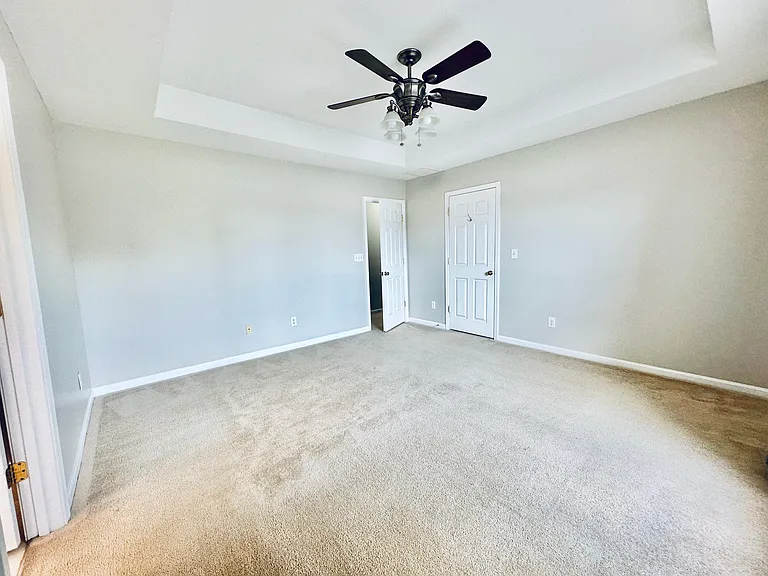Master bedroom with tray ceiling and ceiling fan