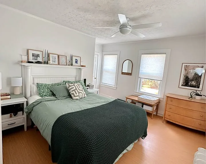 The primary bedroom fits a queen size bed easily and there is a ceiling fan above.