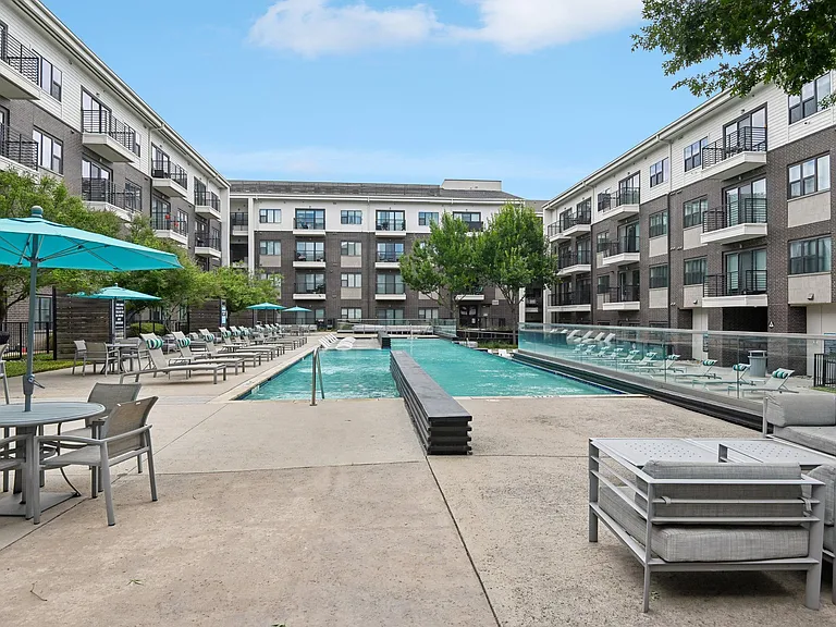 Markethaus 3700 Pool Views from Home A pool area with a table and chairs is surrounded by apartment buildings.