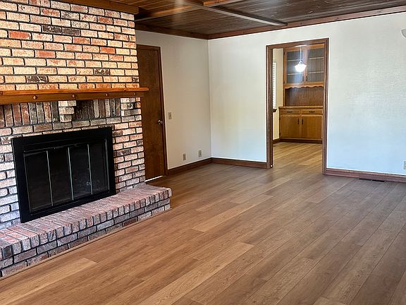 Large living room with custom brick fireplace. The wood ceilings and ceiling fan make this a cozy living space.