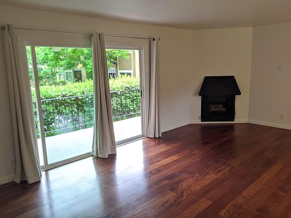 Living room with gas fireplace, double pane slider, gleaming hardwood floors and private balcony over looking pool. Balcony has a storage closet.