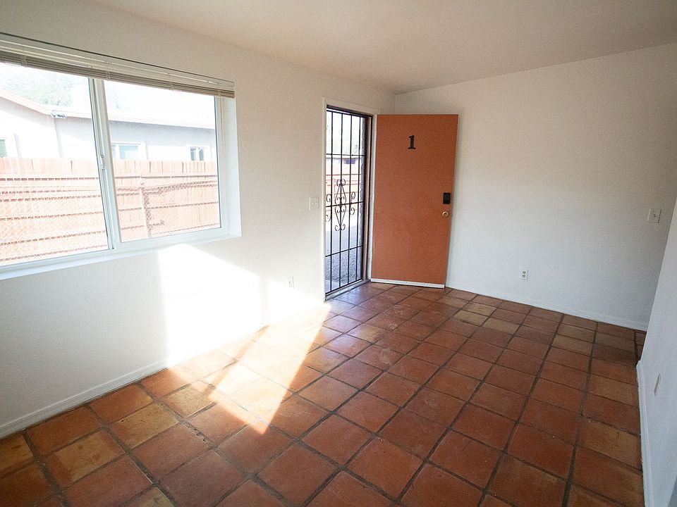 Abundant natural light pours through the living room's large windows, highlighting the handmade saltillo tile underfoot. This bright, open space creates an atmosphere where you can truly breathe and settle in.