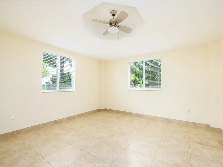 Bedroom with windows on both sides facing west and north freshly painted in light blue grey