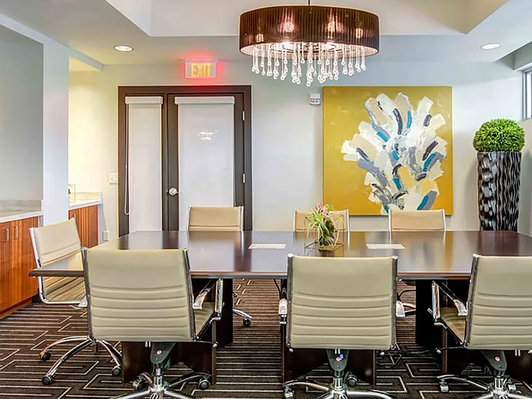 Luxury apartment community conference room with large meeting table, modern lighting, and contemporary artwork
