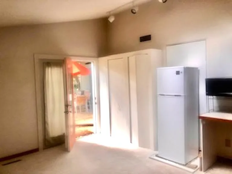 View of front door (west) as exit. Shown here are entry closet & cupboard, refrigerator, partial kitchenette