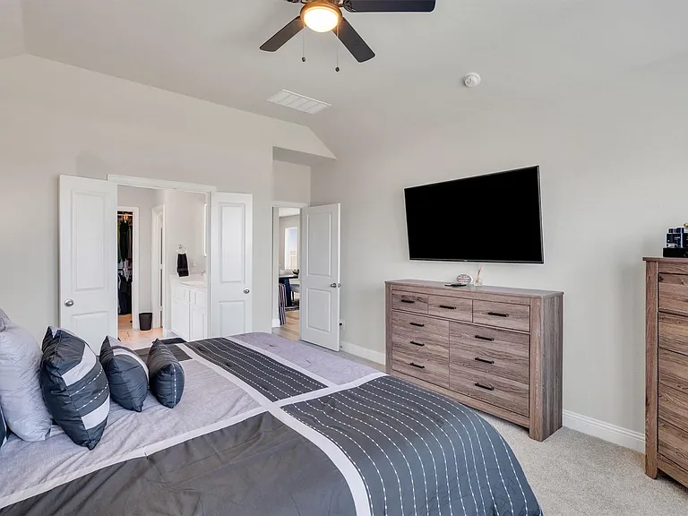 Carpeted sleeping area with light-toned walls and a ceiling fan