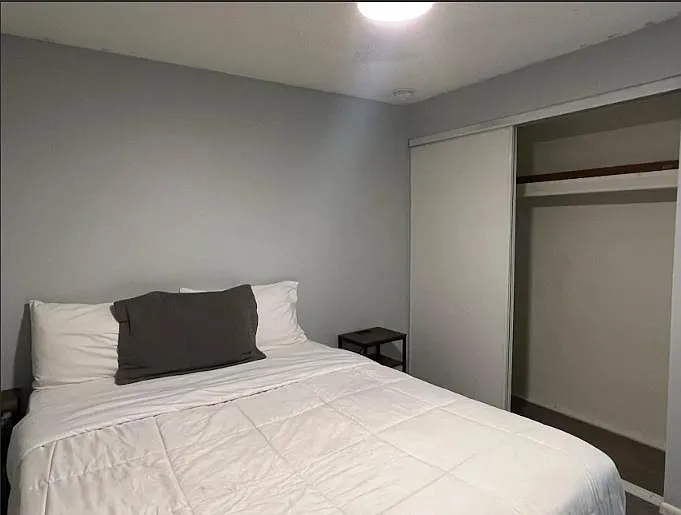 Private bedroom with a full-size bed, bedside table, and a sliding-door closet for convenient storage.