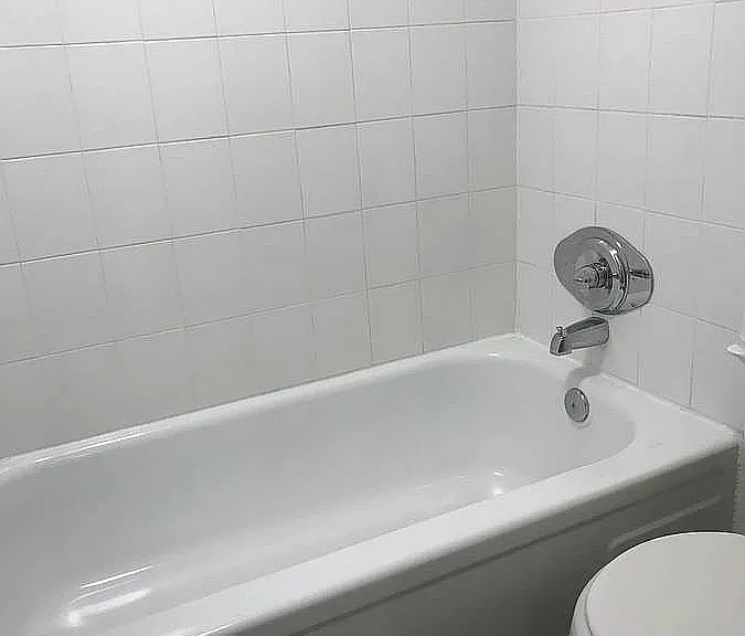 Elegant bathroom with a pristine white bathtub, chic tiled walls, and modern chrome fixtures offering a refreshing retreat.
