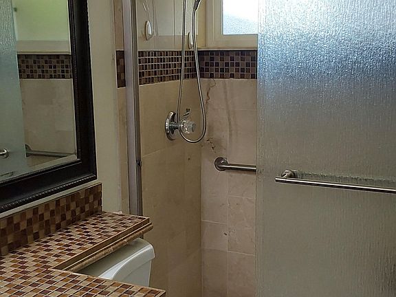 MBR Bathroom.
Custom tile & cabinetry.
Tile floor.
Shower includes custom stone tile w/ trim, adjustable shower head, grab bars and bench seat.