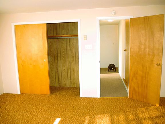 Front bedroom with large closet. View of hallway with walk-up attic on right and full bath on left. BR2 in far view.