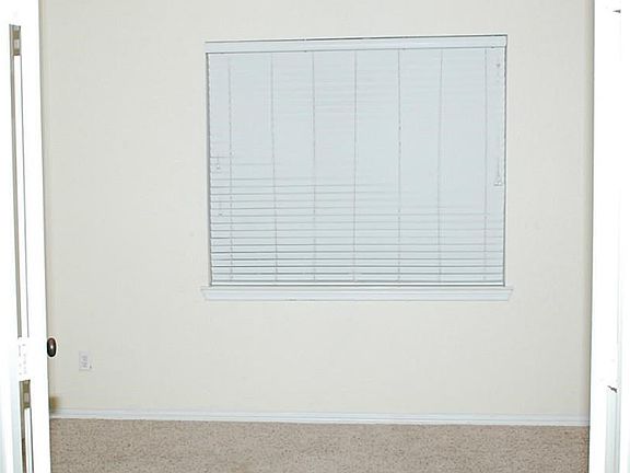 View of the study with carpet flooring and a window that shows the view of the front yard.