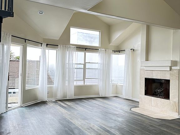 High ceiling living room with recessed lighting, fireplace, access to balcony