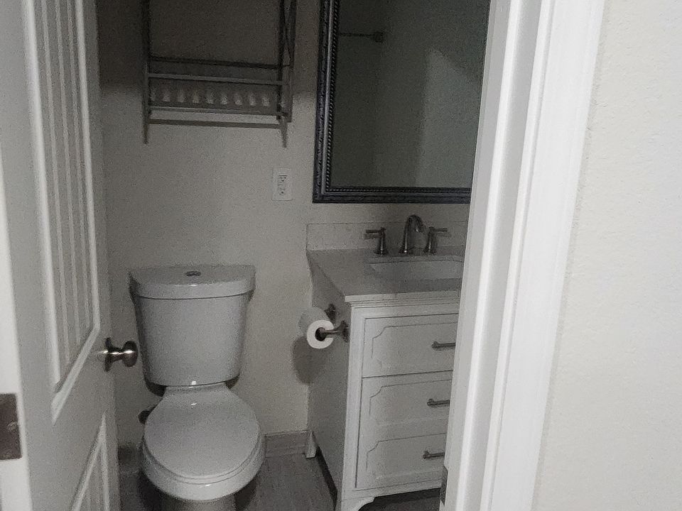 Doorway view into the bathroom. Wash basin with large lighted mirror and cabinet below. Another wall shelving can accommodate bathroom accessories. Also an environmental friendly toilet at your convenience.