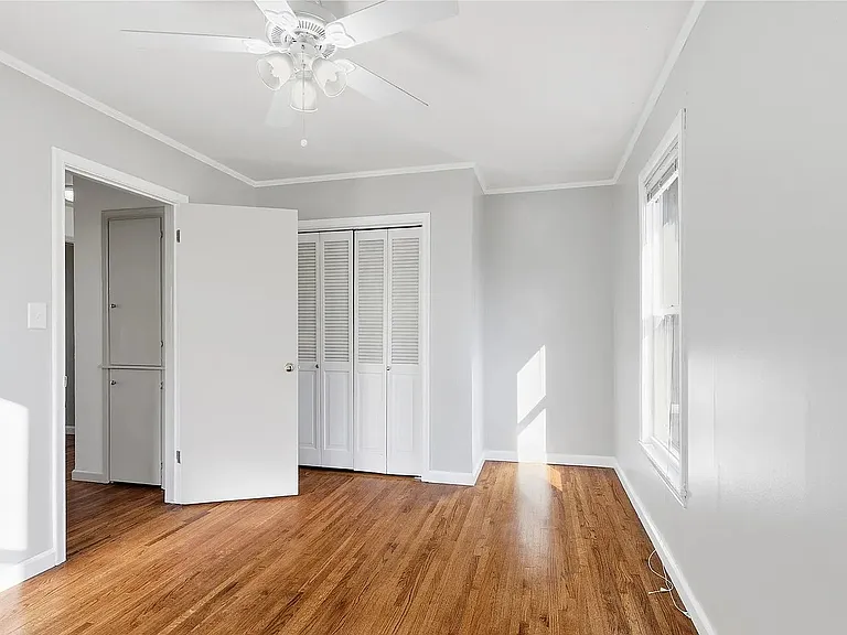 Bright bedroom with hardwood floors, generous closet space, and window blinds for comfort and convenience.