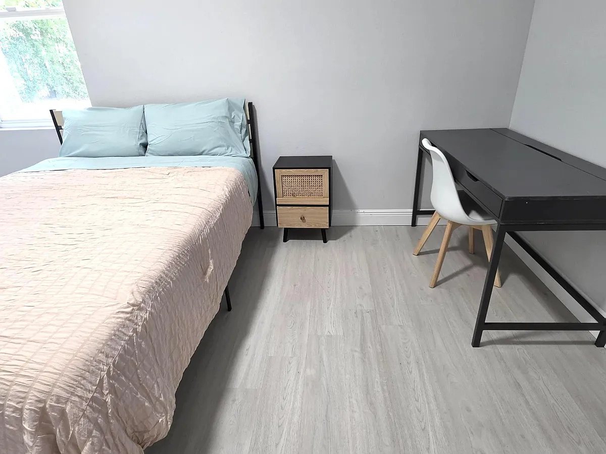 Furnished bedroom featuring a full bed, nightstand, and dedicated desk area, plus a window and easy-care flooring. - Cherry Rd