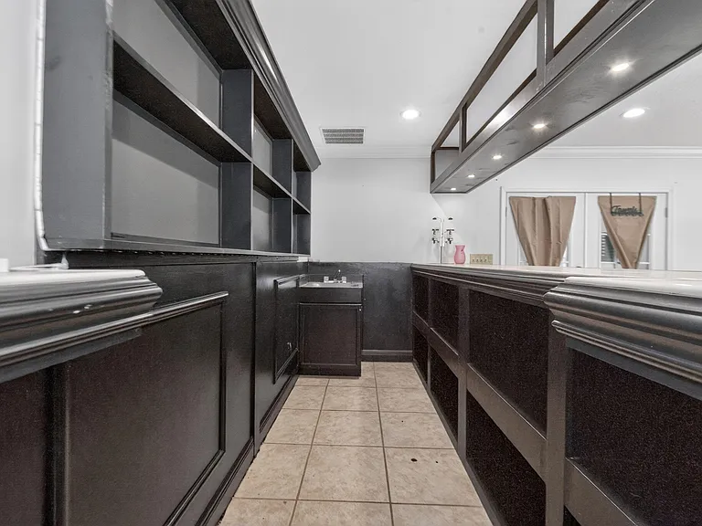 Built-in bar area with extensive shelving, a prep sink, and tiled flooringideal for entertaining and extra storage.