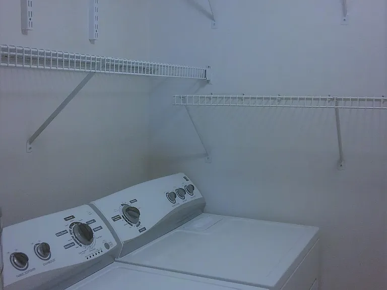utility room with full size washer and dryer inside the unit and extra storage shelves
