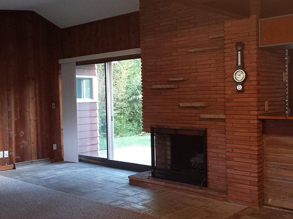 Great room showing fireplace and vaulted ceiling. Sliding door to patio. Kitchen door to patio (right side) behind bar.