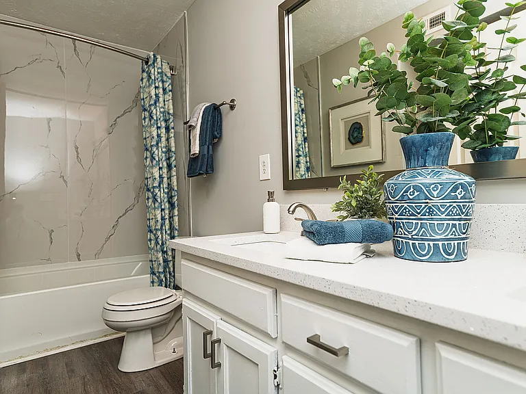 Bright bathroom with granite counters and bathtub with marble backsplash