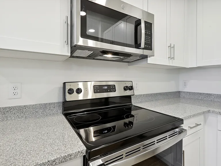 Modern kitchen with sleek stainless steel appliances, granite countertops, and elegant white cabinetry.