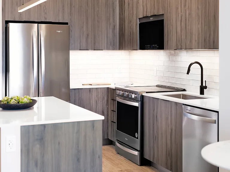 Upgrade Collection II kitchen with espresso cabinetry, white tile backsplash, stainless steel appliances, and hard-surface vinyl plank flooring