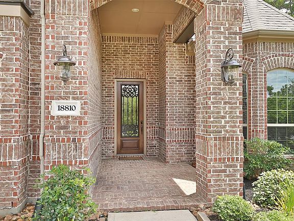 WELCOMING ENTRY: Details matter, and the brick flooring on the entry porch, coupled with the mahogany door with iron work, are the details that you can expect in a home built by well respected Village builders. Coach lights flank either side of the f