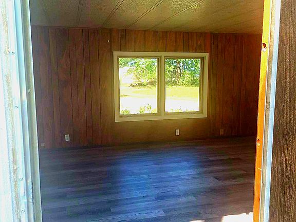 Front door entrance into spacious living room with lots of windows and trees surrounding the property.