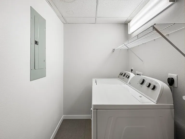 Modern laundry room featuring a sleek washer and dryer, ample shelving, and bright overhead lighting. Modern laundry room featuring a sleek washer and dryer, ample shelving, and bright overhead lighting.