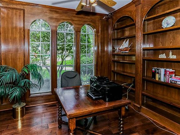Private study with warm wood bookcases and flooring offers quiet space for work and concentration.