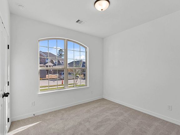 Bright and cozy second bedroom with plush carpet and sun-filled windows.