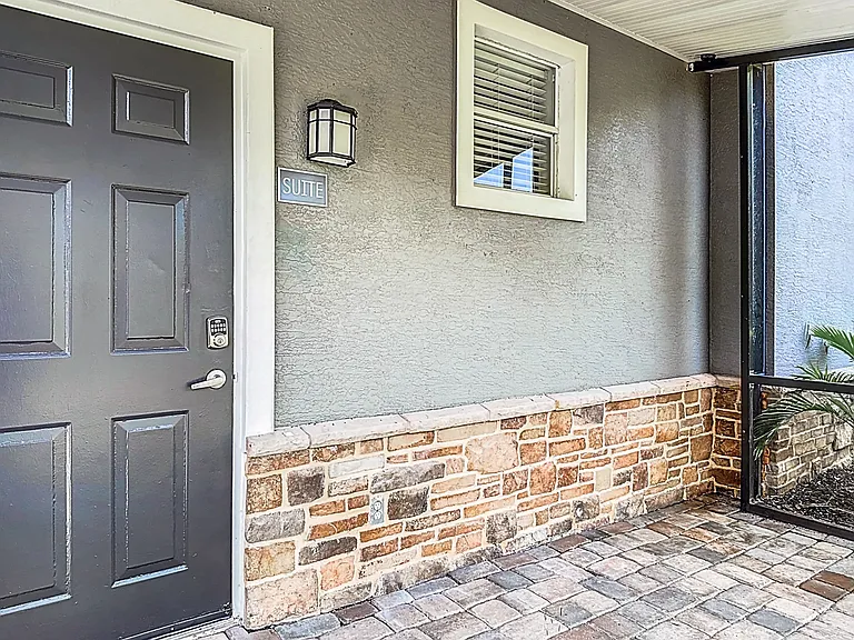 The Suite entrance offers a charming and secure entry to your home with stone accents and a cozy screened in patio