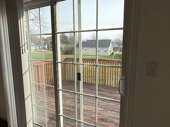 The sliding glass door provides a clear view of the deck, allowing natural light to flood the room. The deck itself is spacious, ideal for outdoor activities and enjoying the scenery. The view includes well-maintained surrounding green spaces.