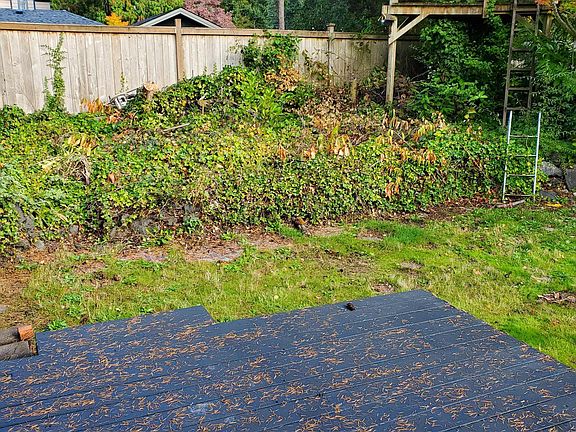 Deck in backyard; partially fenced; mature landscaping