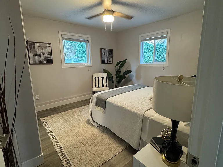 Spacious bedroom with ceiling fan, large windows, and luxury vinyl plank flooring.