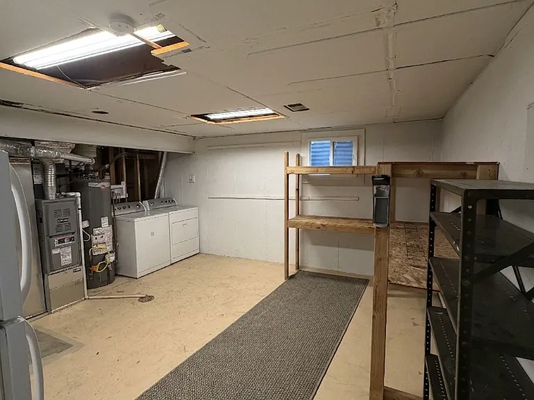 Large basement workshop/storage area where the washer, dryer, and extra fridge/freezer are located