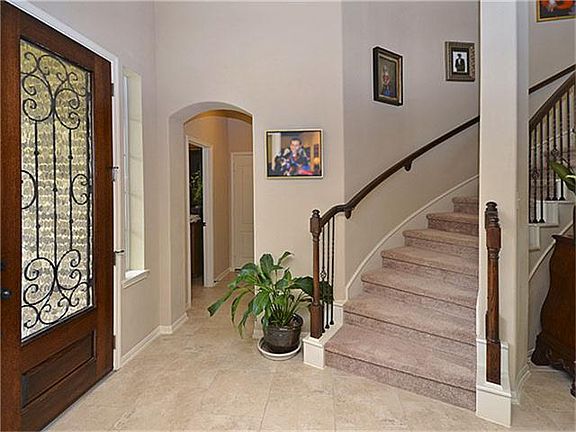 An 8 ft front door with 3/4 glass accented by wrought iron grille work anchors the entry and leads into the stunning 18 ft Rotunda Foyer.