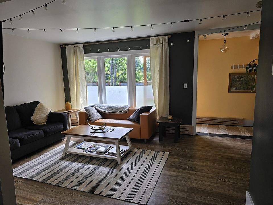 Living room features a comfortable sofa bed and a 50' wall-mounted smart TV with lots of natural light. A stacked washer and dryer are in a closet to the right of this room.