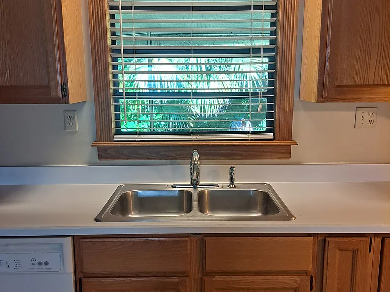 Kitchen has lots of cabinets for storage, dishwasher and double stainless steel sink.
