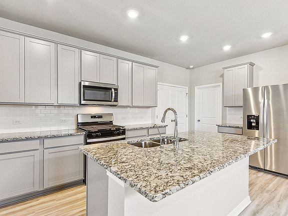 The kitchen features stone-colored cabinets and granite countertops.